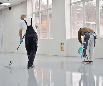 Двама мъже, предлагащи ремонтни услуги почистване на пода на офис сграда.