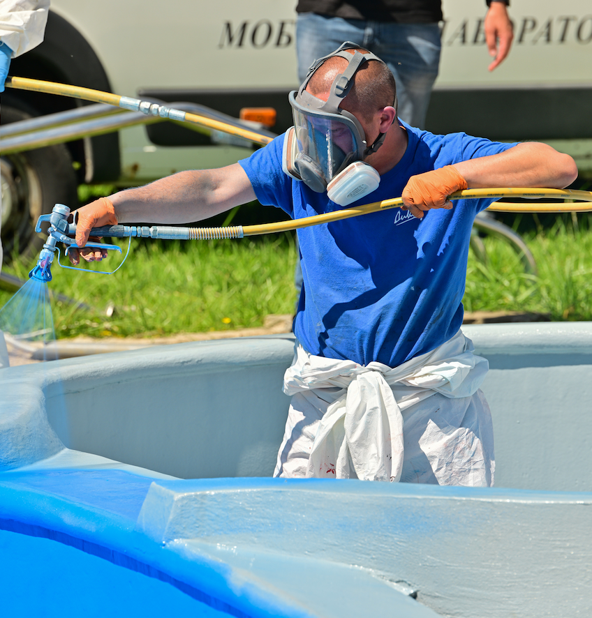 Мъж, използващ DIXIPRO, пръска боя върху син басейн.