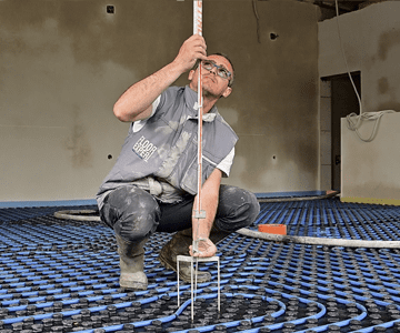 Мъж измерва пода в стая за ремонтни услуги.