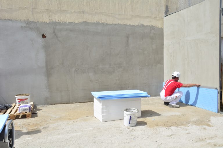 Човек работи върху бетонна стена.